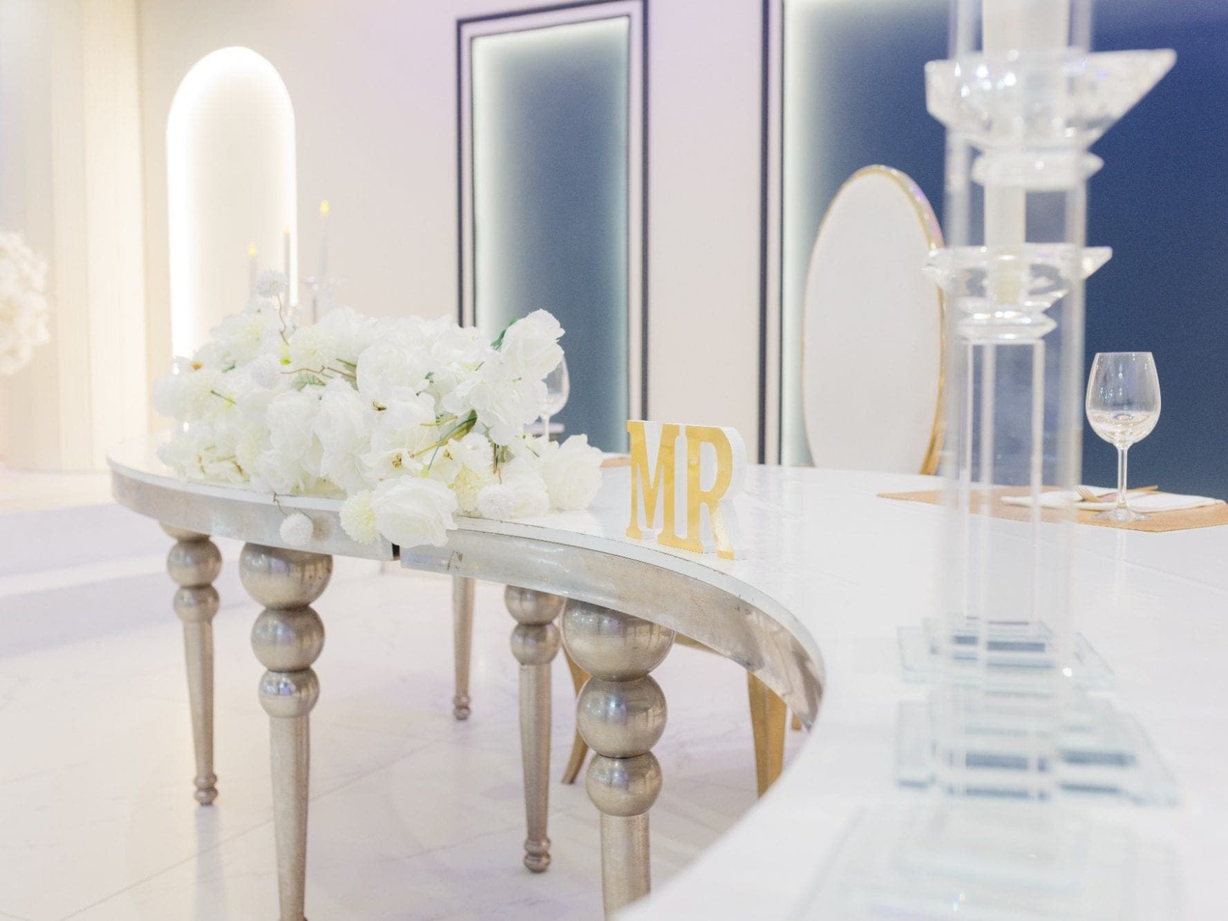 A wedding reception table with white flowers and "MR" sign.