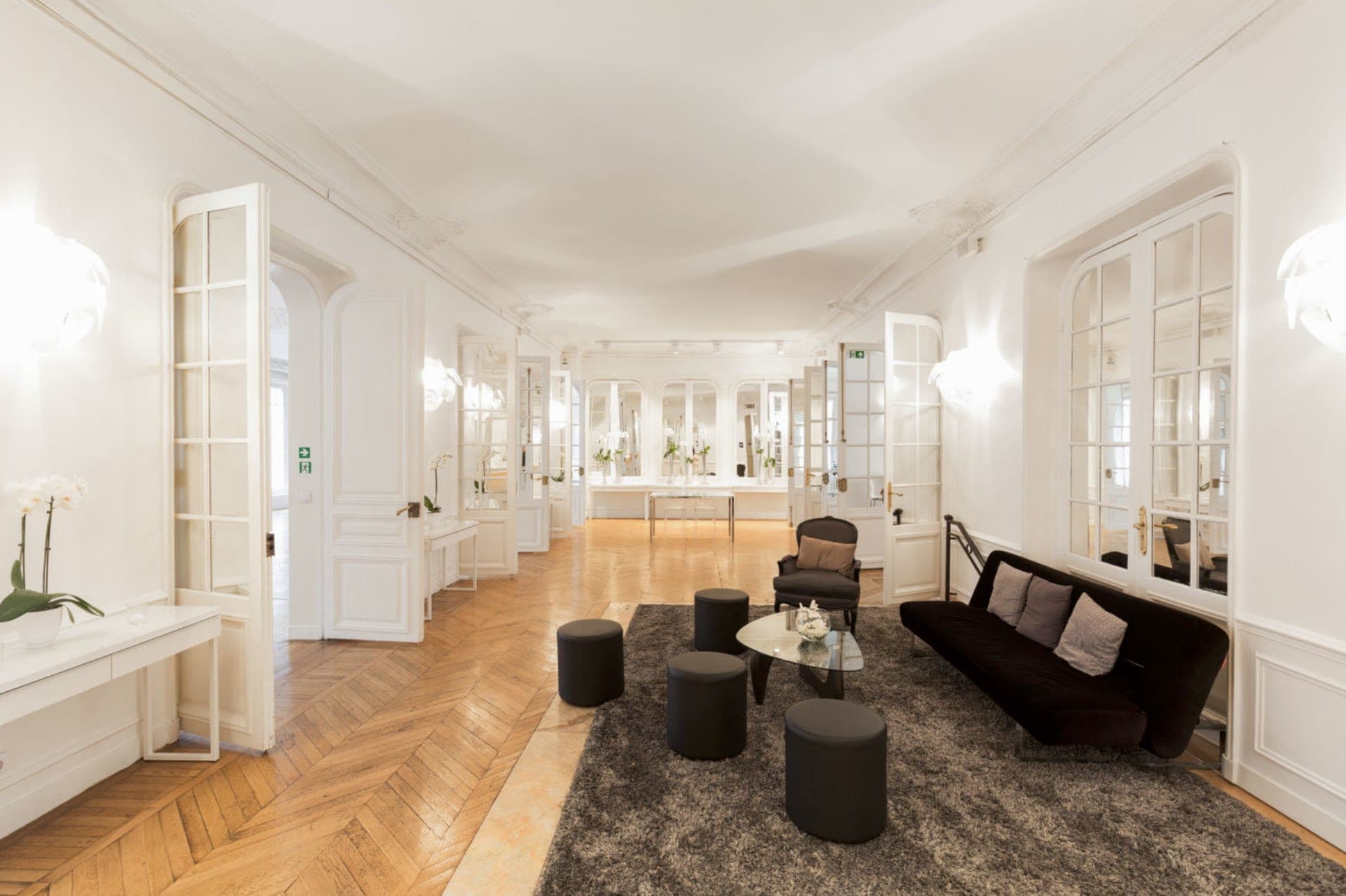 Interior reception area with a sofa, armchairs, coffee table, and multiple doorways.