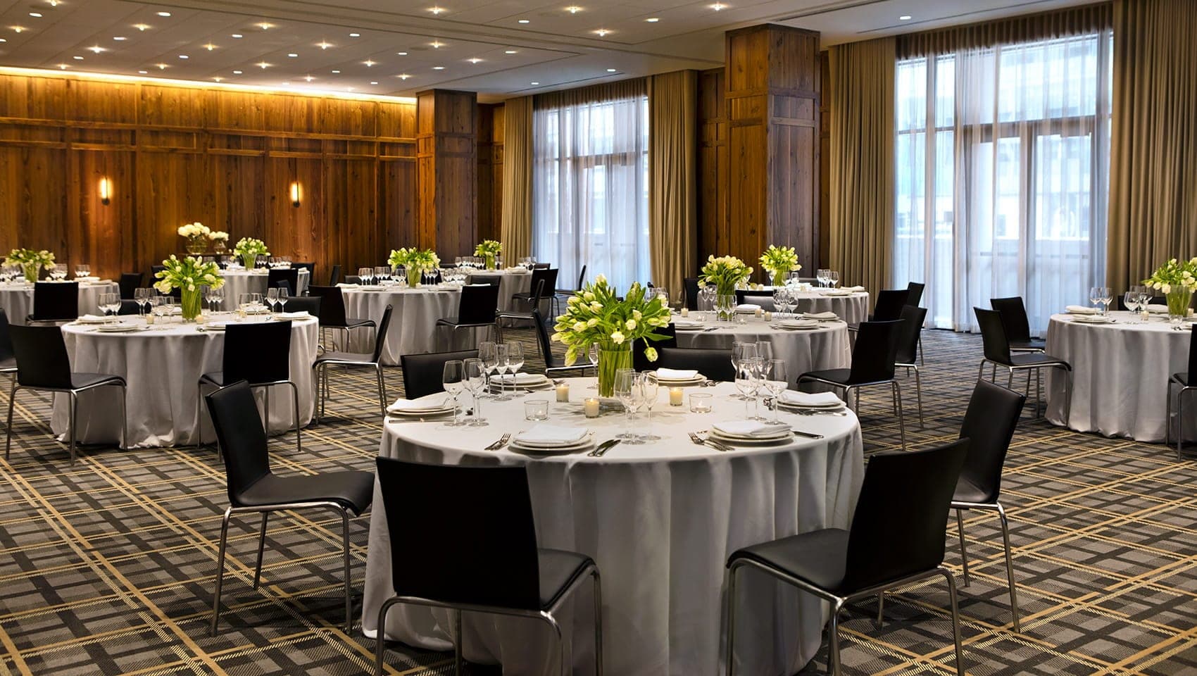 A reception room with round tables set for a wedding.