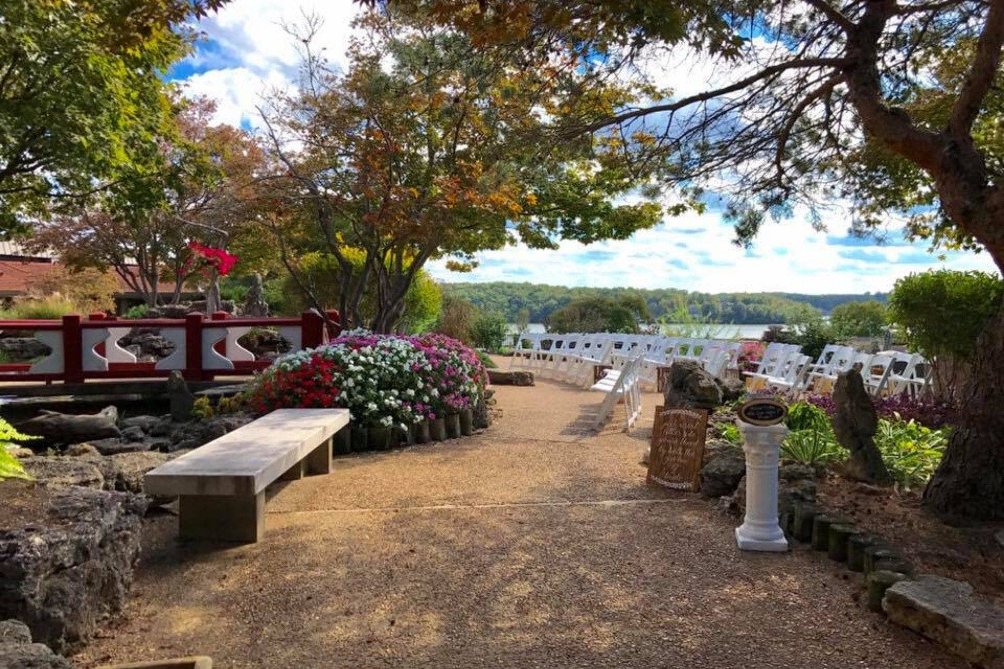 Outdoor wedding ceremony setup with white chairs facing a lake