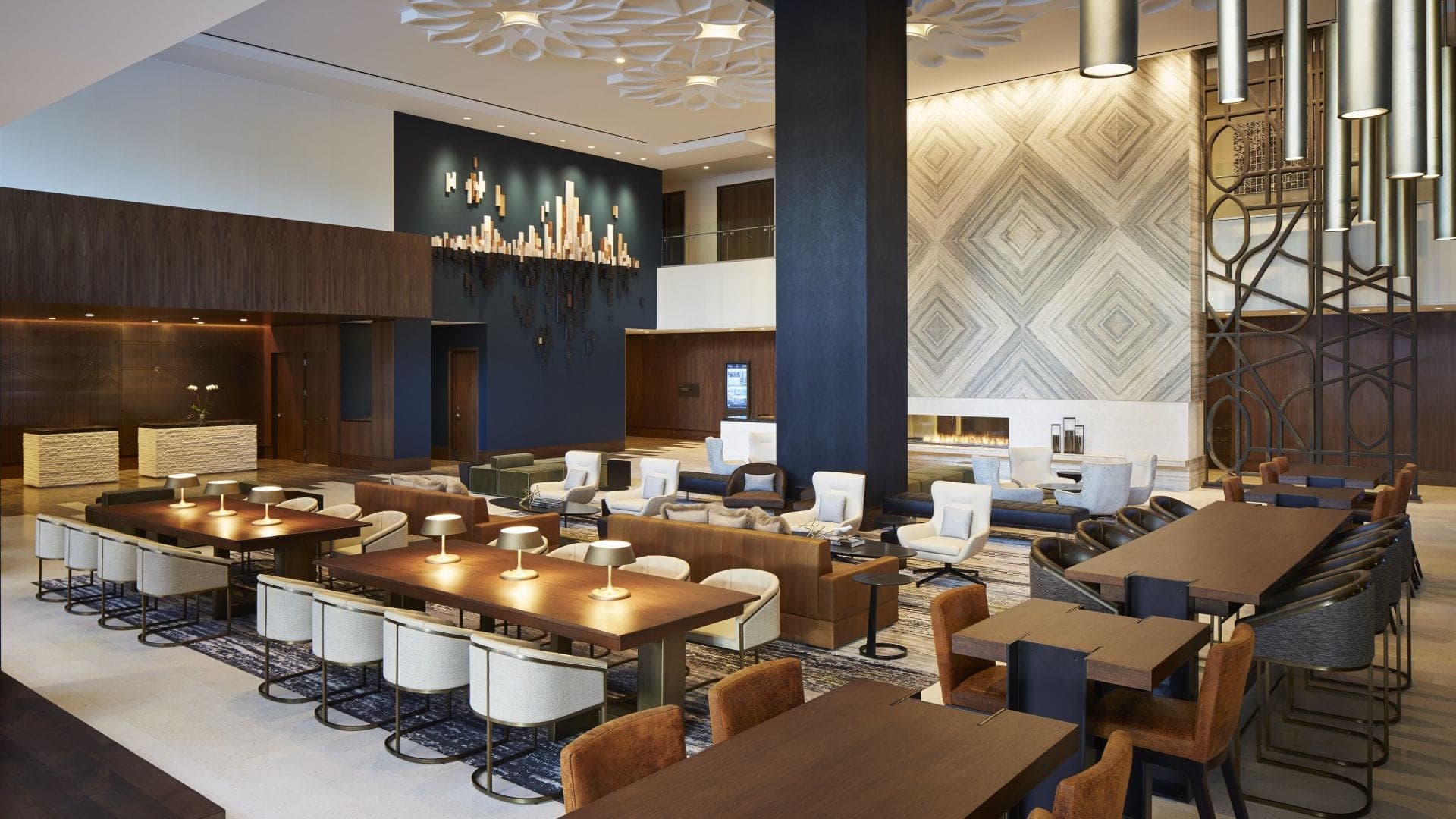 A hotel reception area with tables, chairs, and a fireplace.