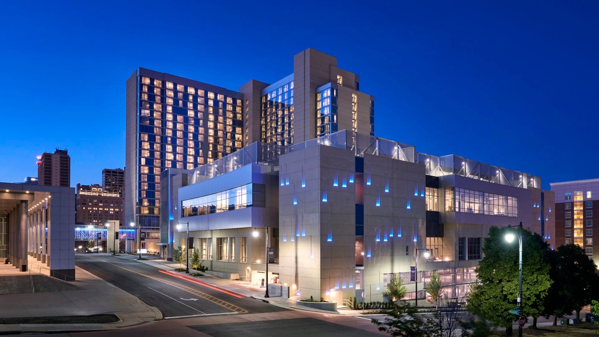 Exterior of Loews Kansas City hotel at dusk with city lights.