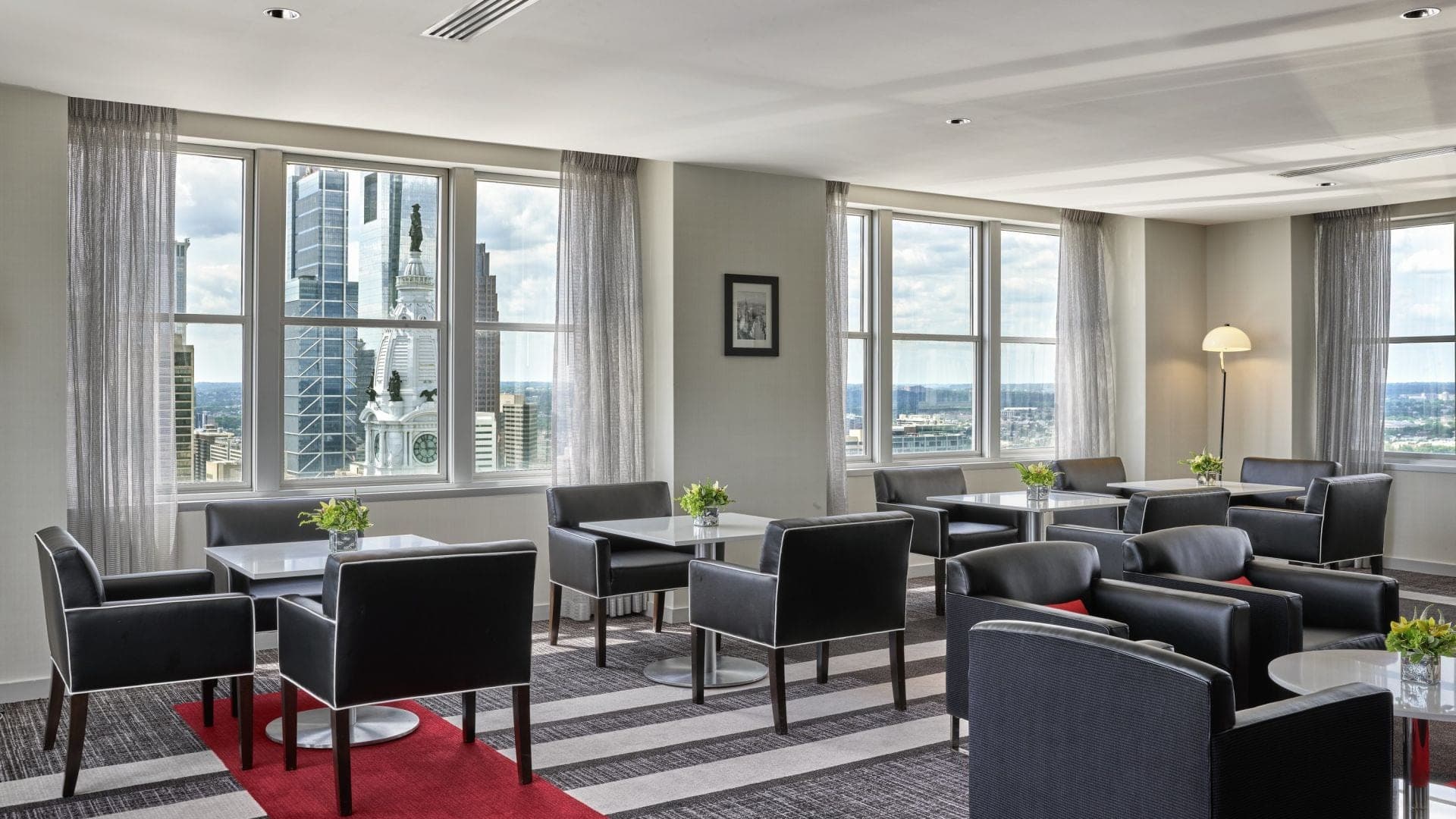 A room with seating and tables overlooking a city skyline.