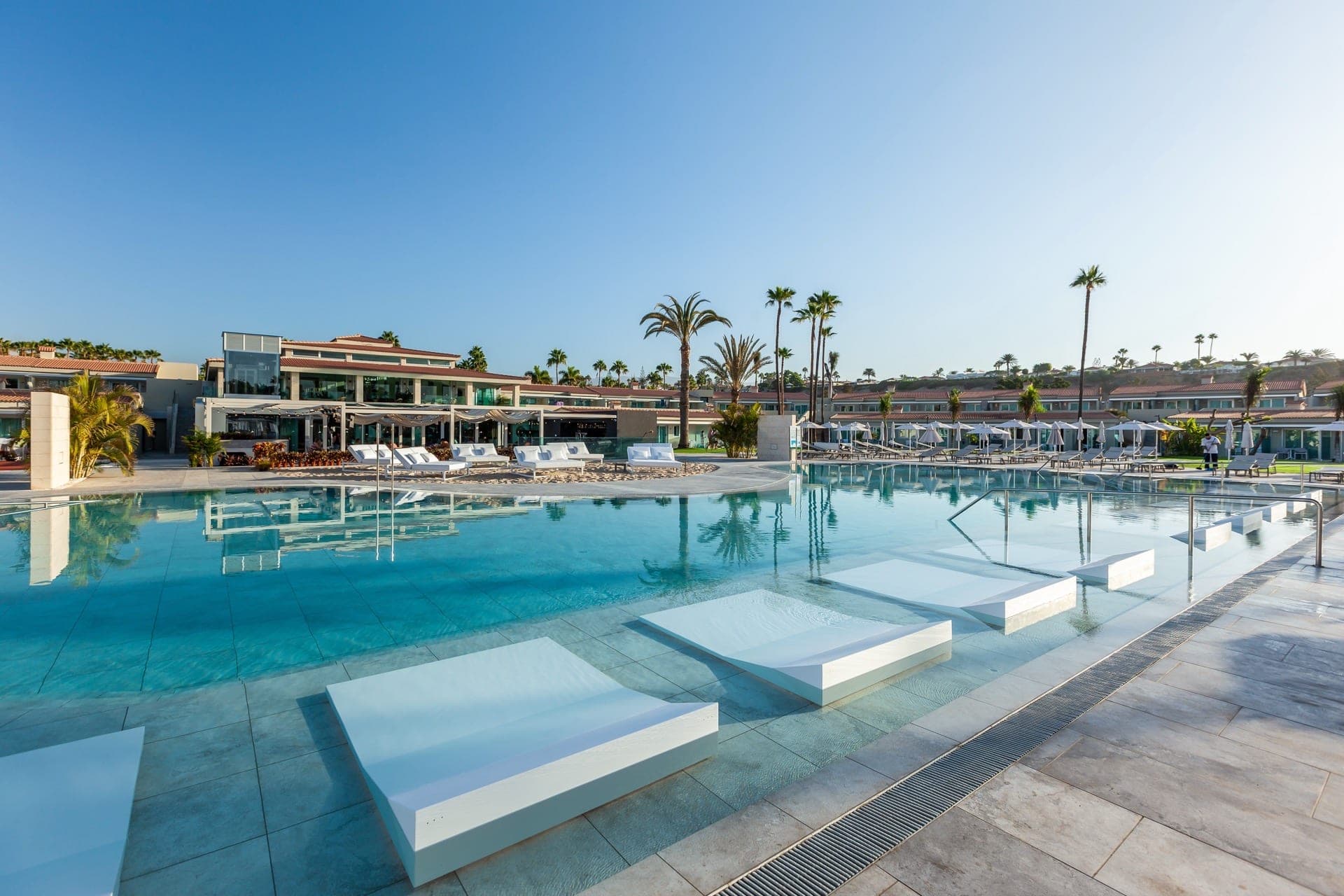 Resort with a swimming pool and palm trees under a clear blue sky.