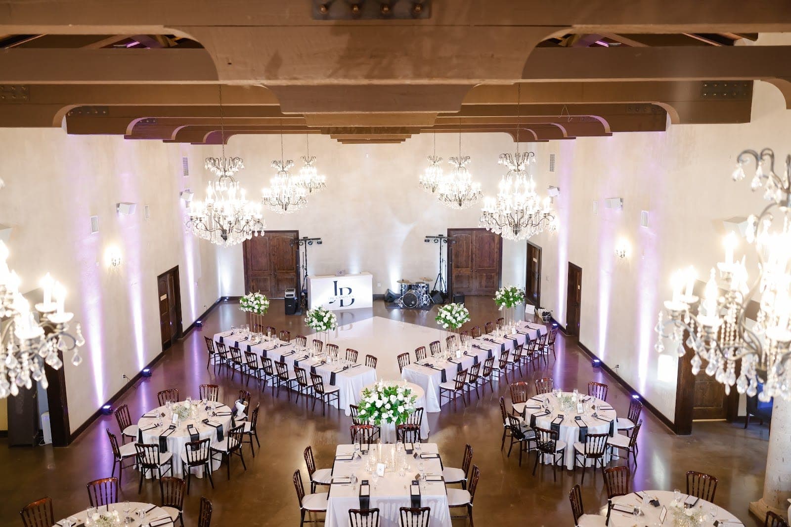 A reception hall with tables, chairs, and chandeliers.