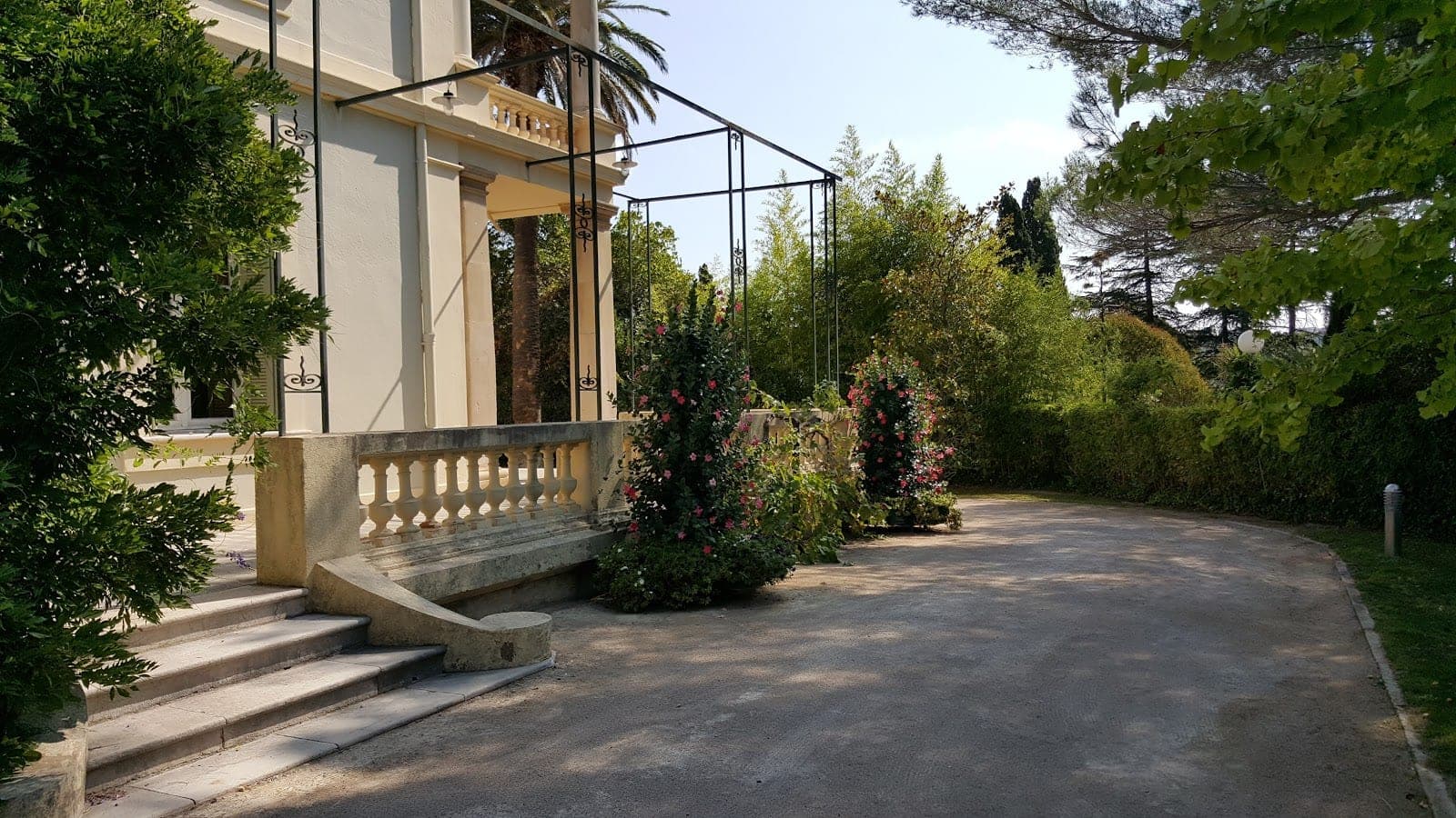 Exterior of a building with a balcony, stairs, and garden.