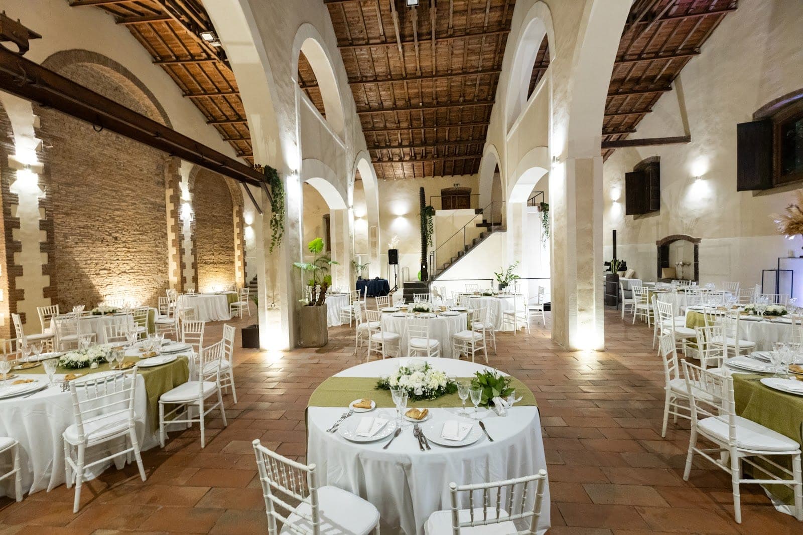 Wedding reception hall with round tables and white chairs.
