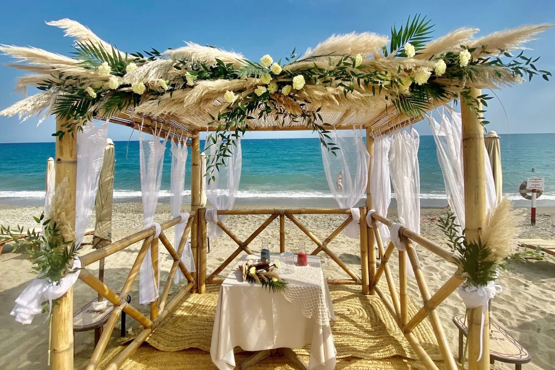 Beach wedding arch with white flowers and pampas grass, overlooking the sea.