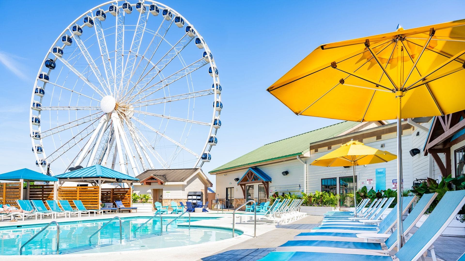 Swimming pool with lounge chairs and a Ferris wheel in the background.