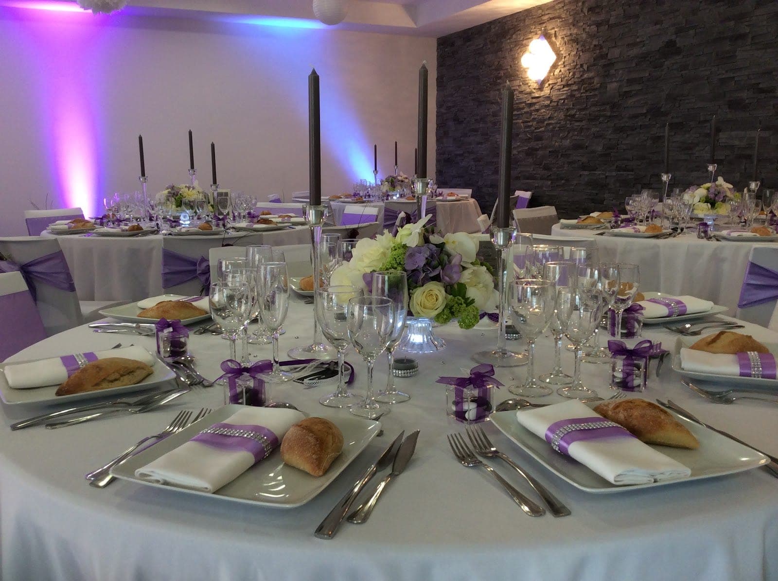 A reception room with tables set for a wedding with purple accents.