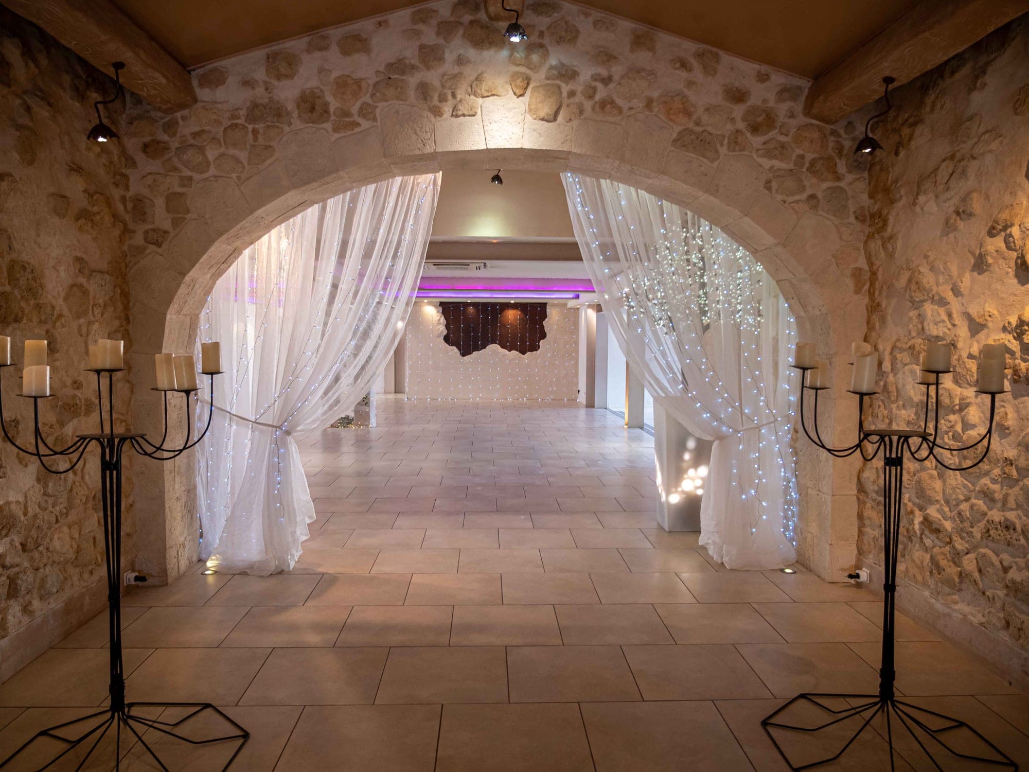 Empty reception hall with stone walls, archway, and fairy lights.
