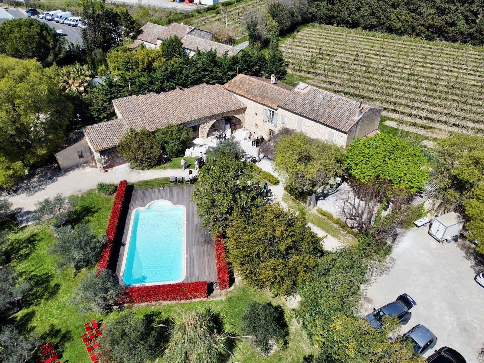 Aerial view of a wedding venue with buildings, a pool, and vineyards.