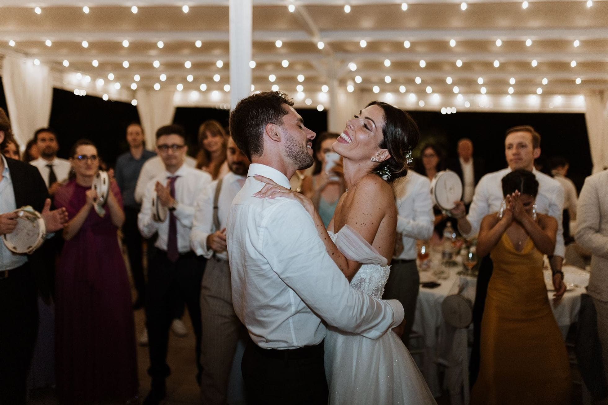 A couple dances at their wedding reception while guests watch.