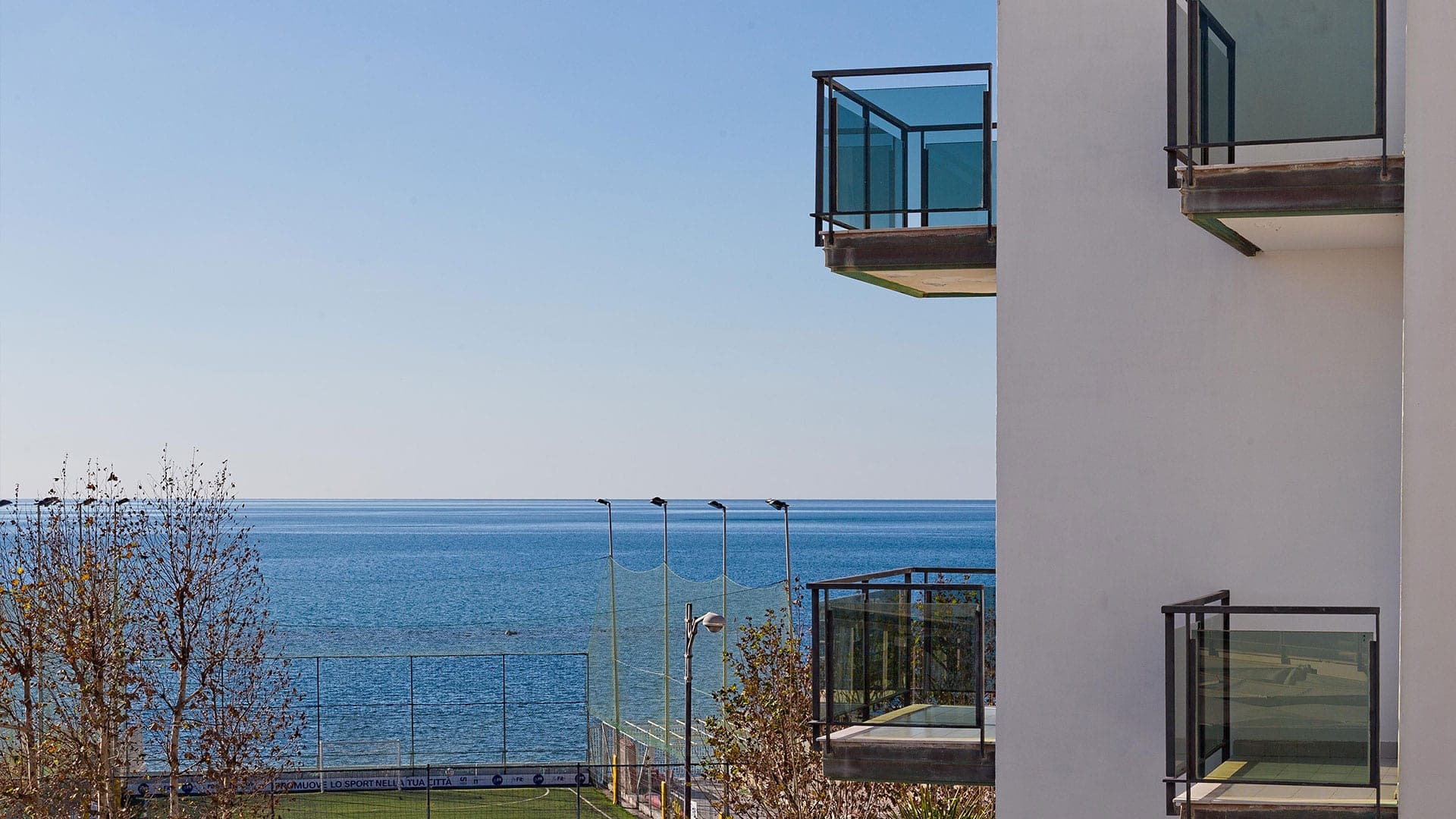 Balconies overlook the sea and a sports field.