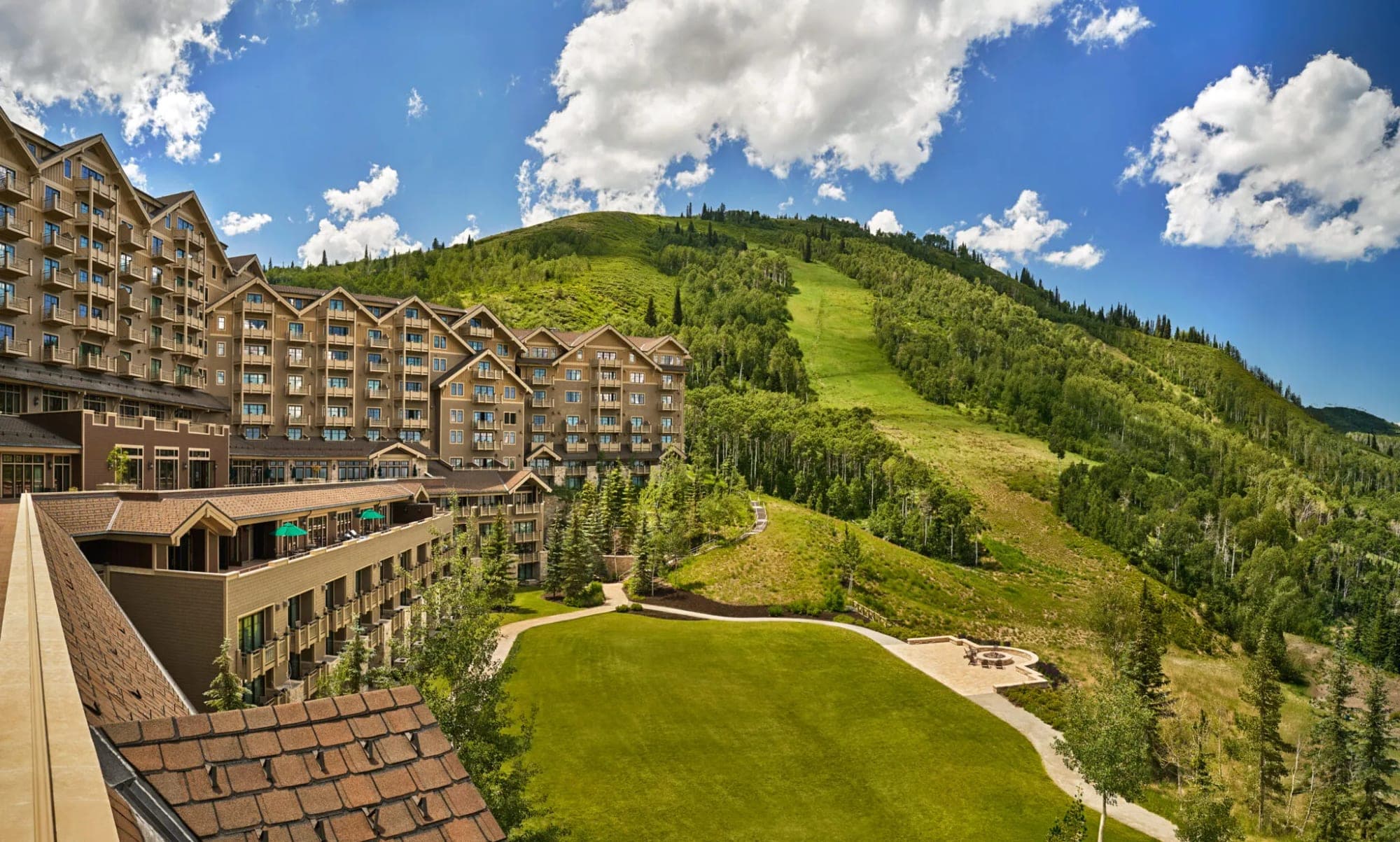Exterior of a large hotel building with a mountain ski slope in the background.