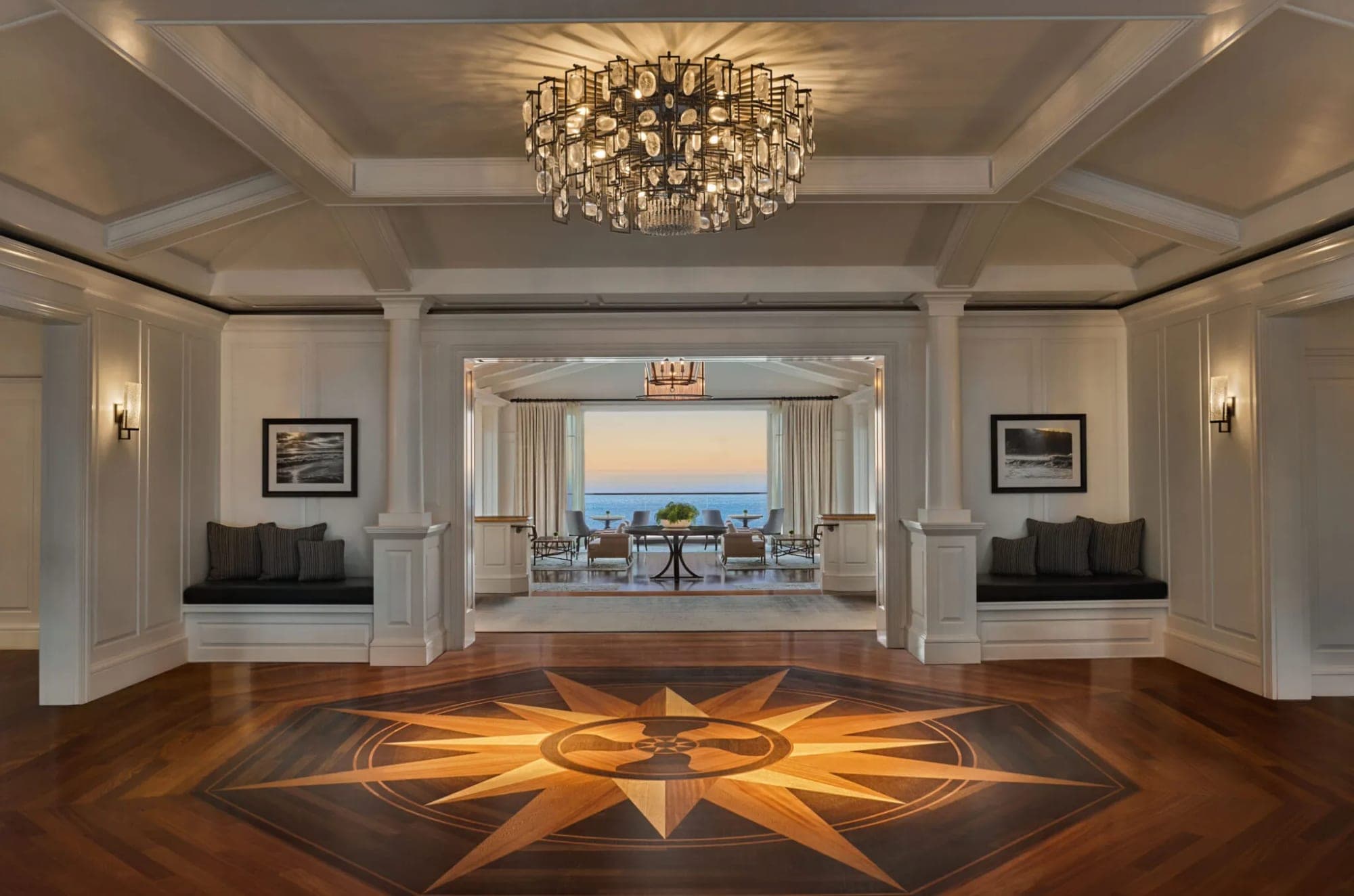 Interior of a venue with a compass rose inlay on the floor and a view of the ocean through an archway.