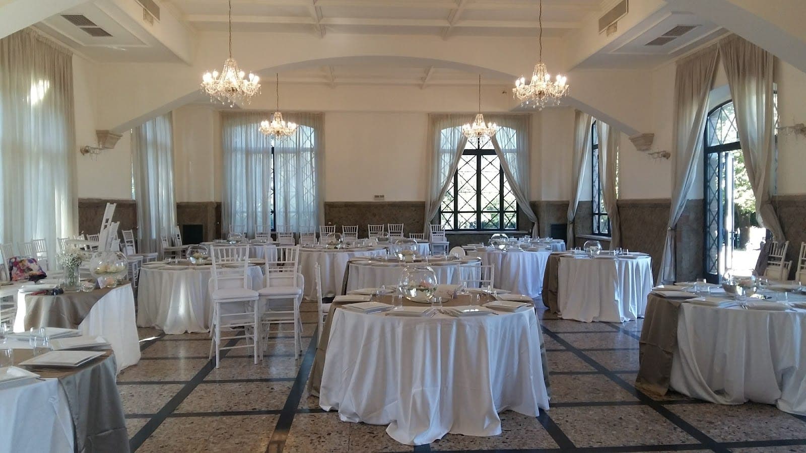 A reception room with round tables set for a wedding.