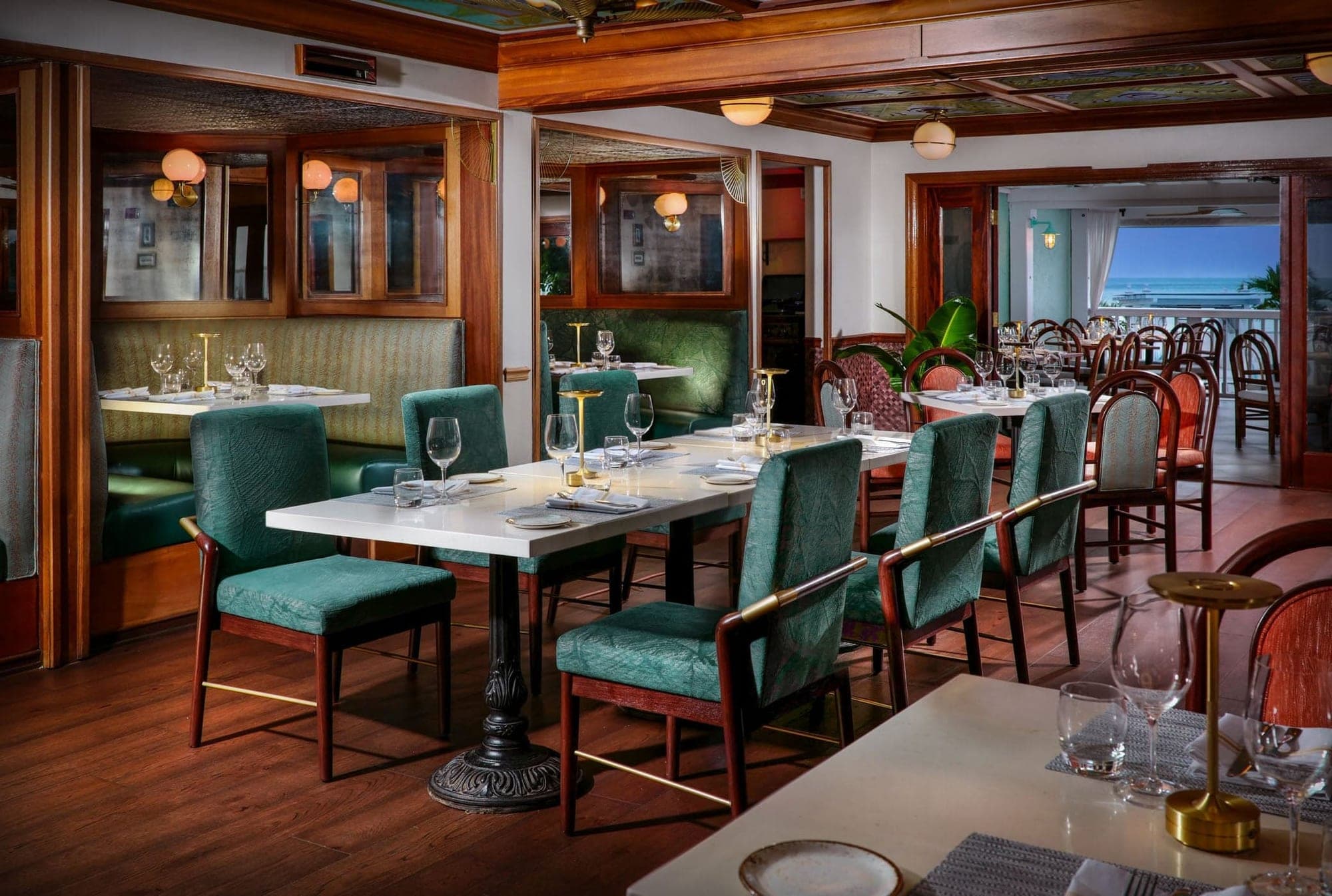 A dining room with tables set for a meal, overlooking the ocean.
