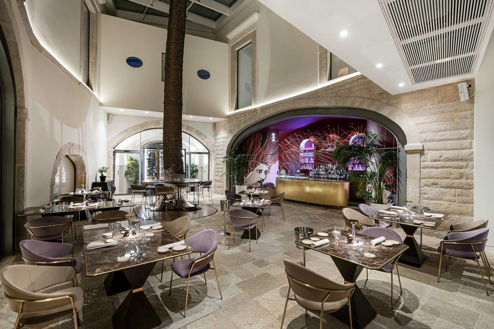 Interior dining room with tables, chairs, a bar, and a large tree.