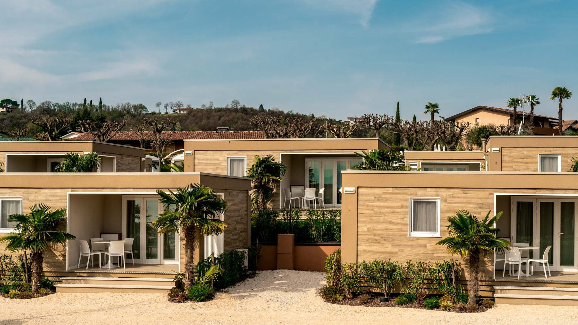 Exterior of resort bungalows with outdoor seating and palm trees.