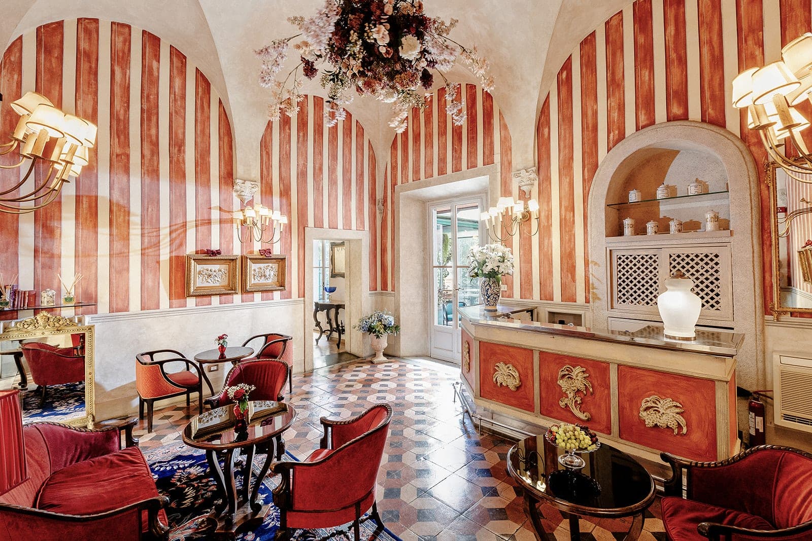 A reception area with red velvet seating and a bar with ornate details.