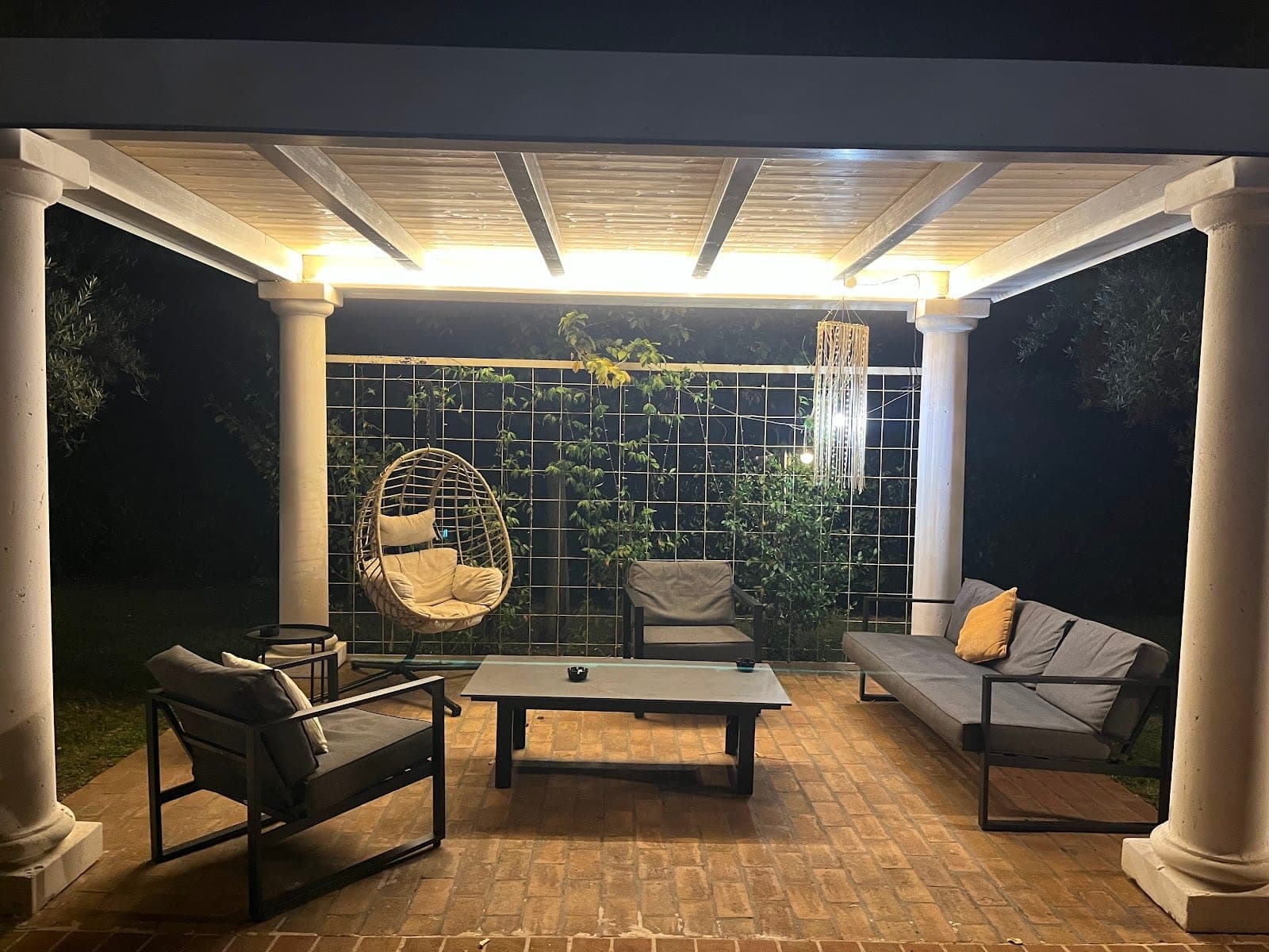 Covered patio with seating and hanging chair at night