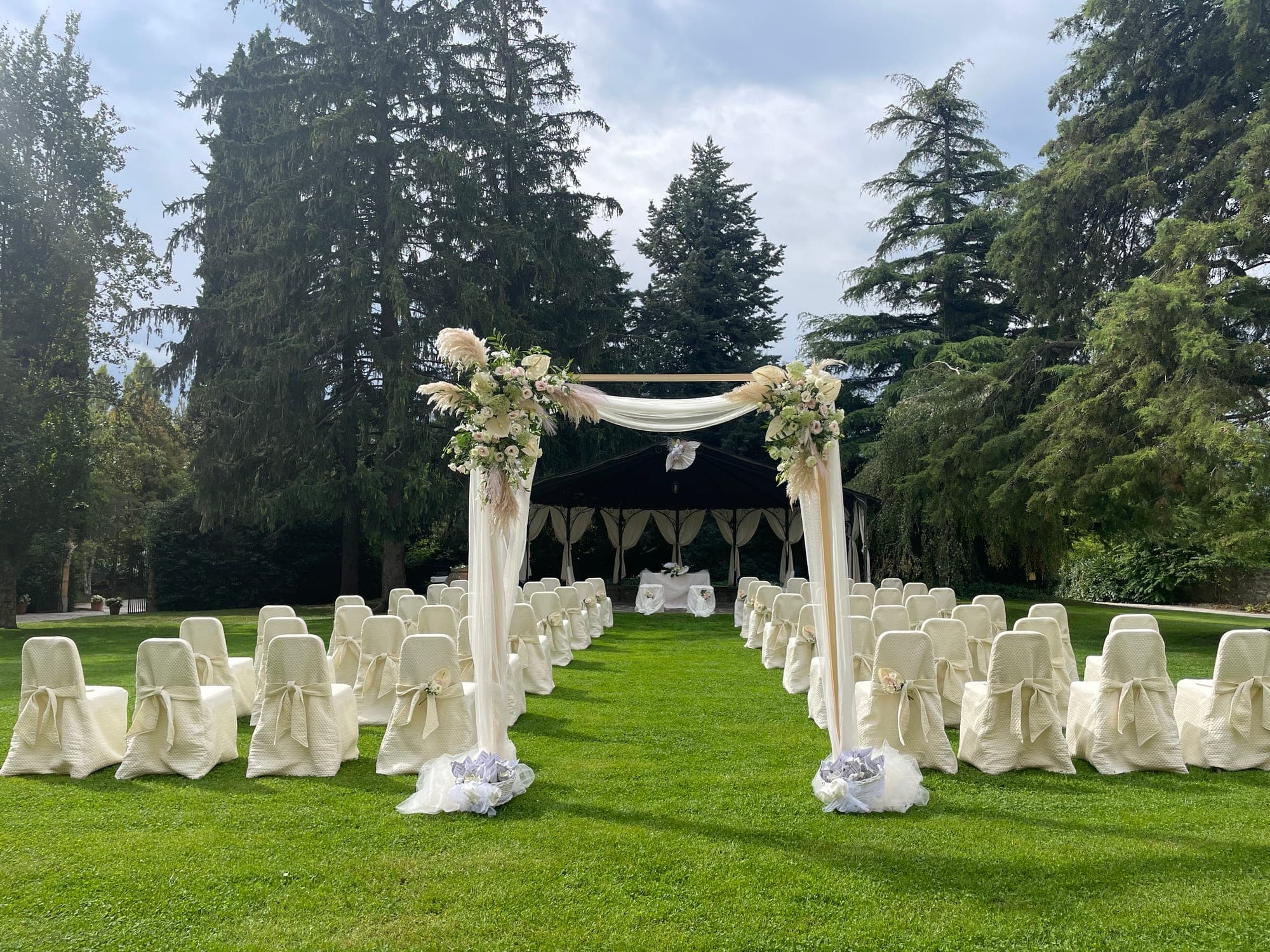 Wedding ceremony setup on a green lawn with chairs and an arch.