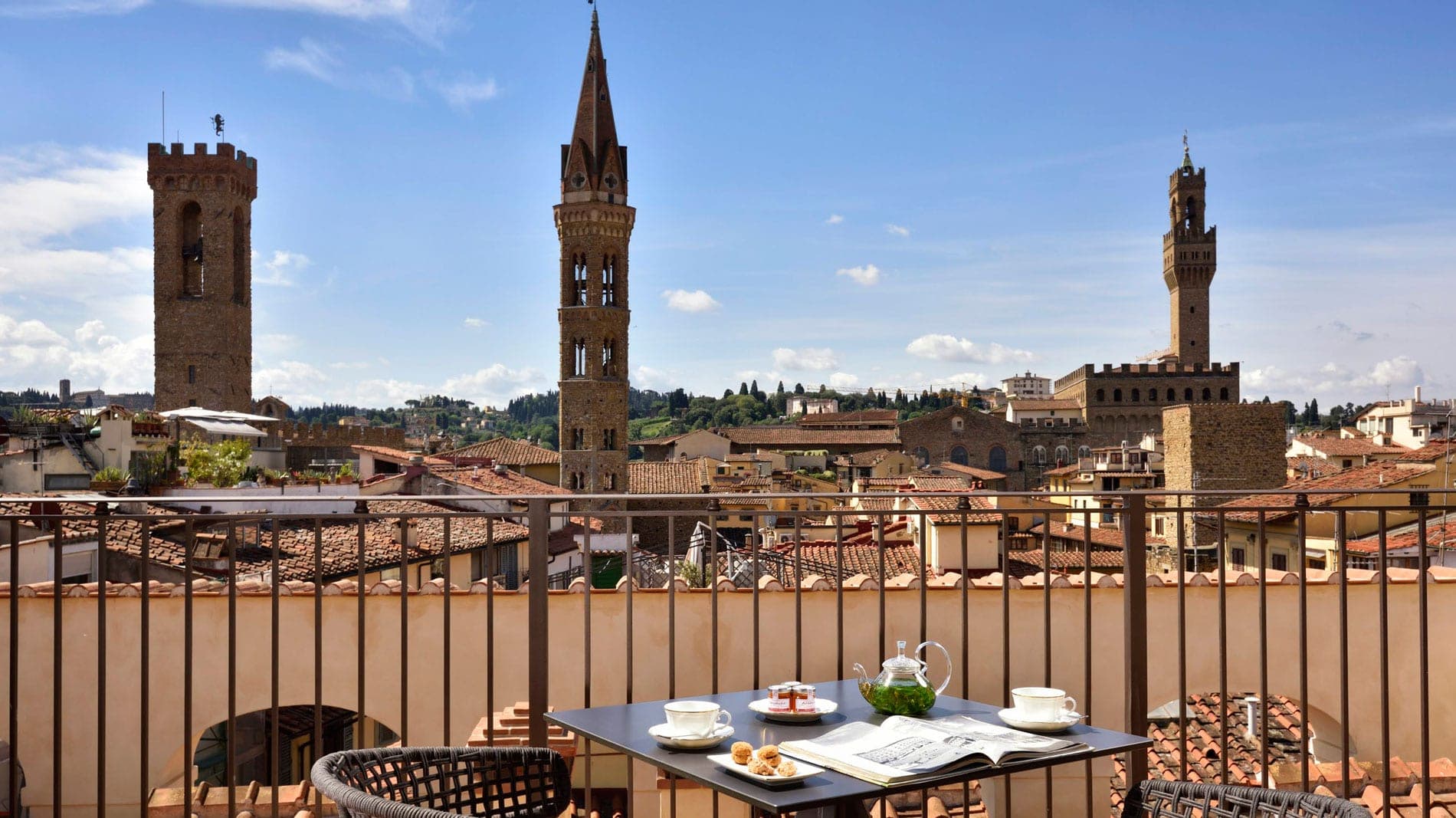 View of Florence rooftops and towers from a balcony with a table set for tea.