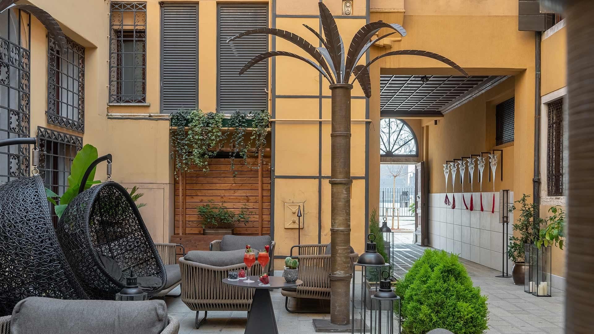 Courtyard with hanging chairs, seating, and a decorative palm tree.