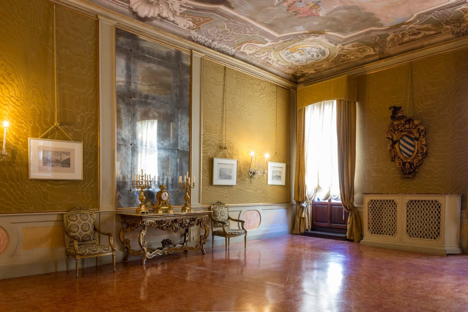Ornate room with gilded furniture, a large mirror, and a frescoed ceiling.
