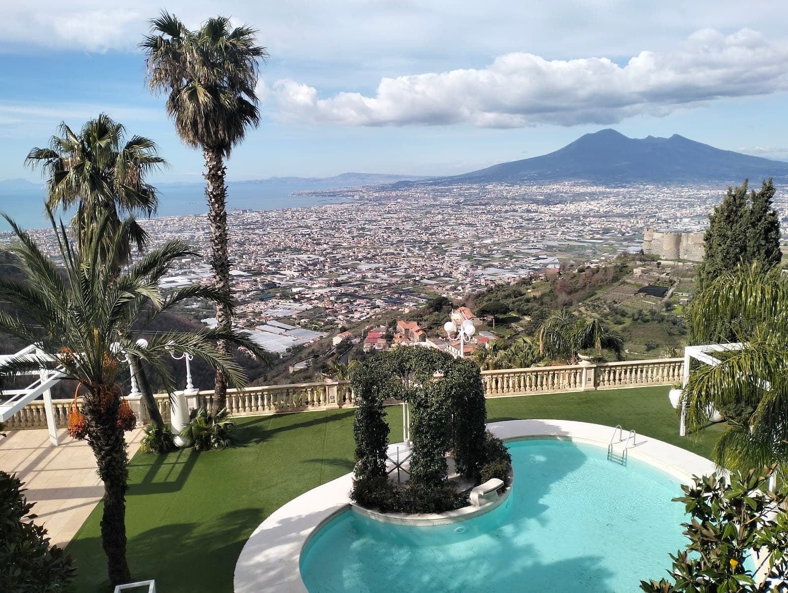 Swimming pool with a view of a city and Mount Vesuvius.