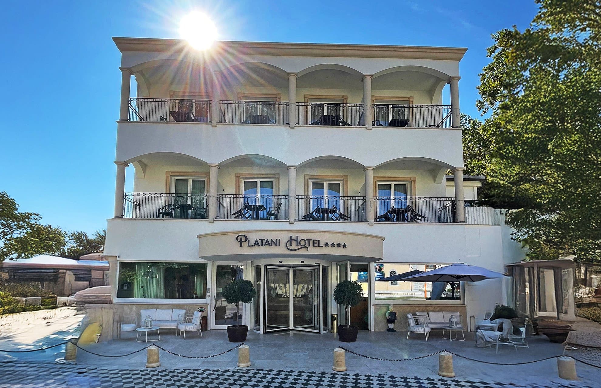 Exterior of Platani Hotel with balconies and entrance on a sunny day.