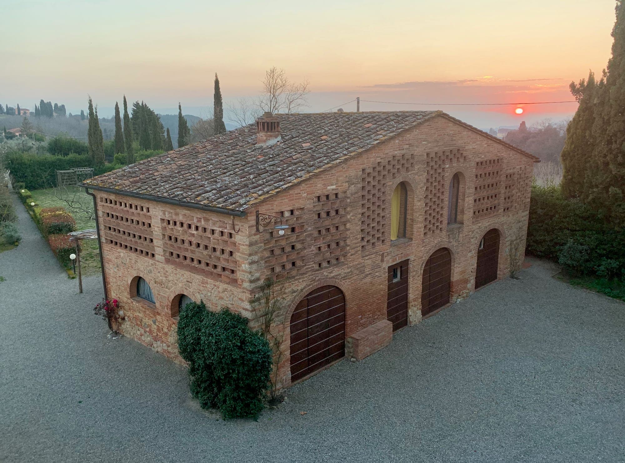 A brick building with arched doorways and windows at sunset.