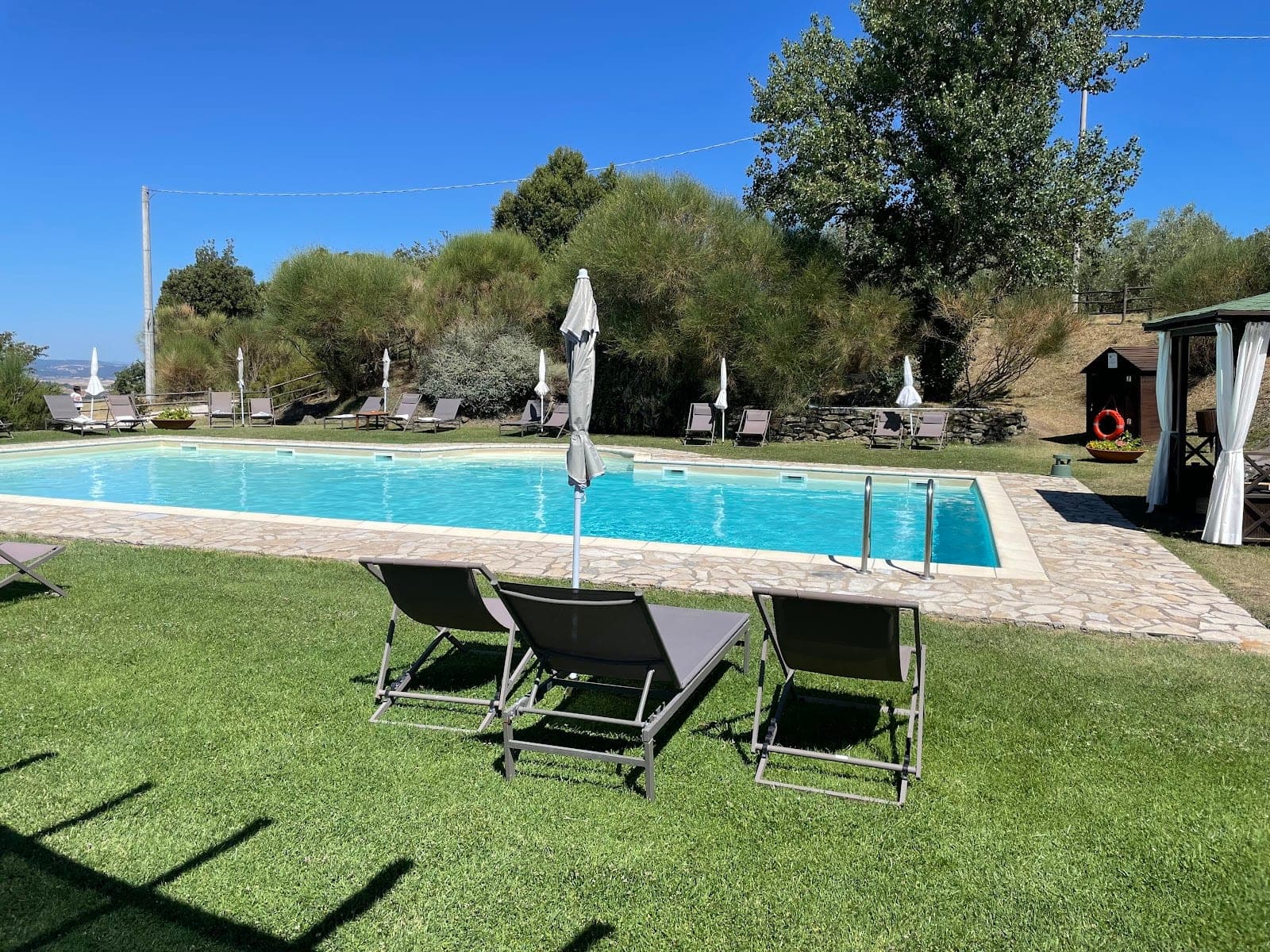 A swimming pool with lounge chairs and umbrellas on a sunny day.