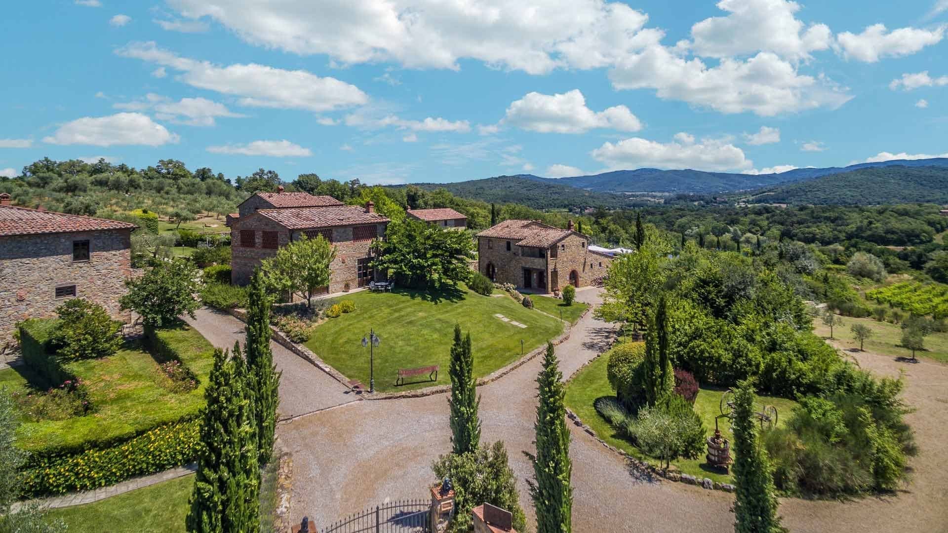Aerial view of Poggio Cennina Resort with stone buildings and green landscape.