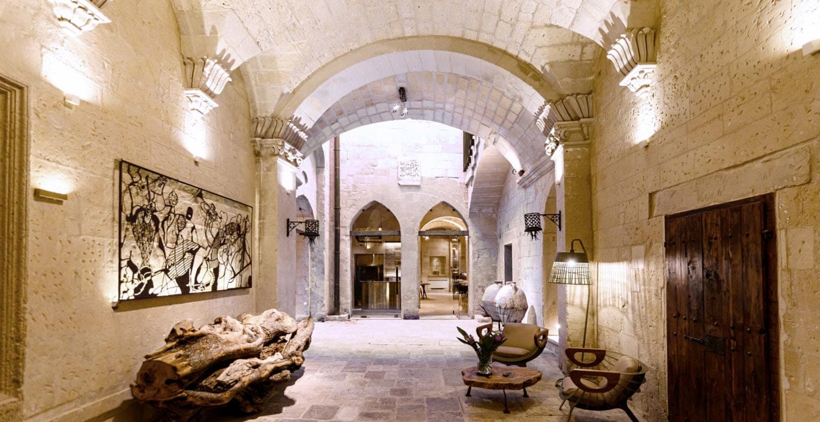 Interior courtyard of a boutique hotel with stone arches and seating.