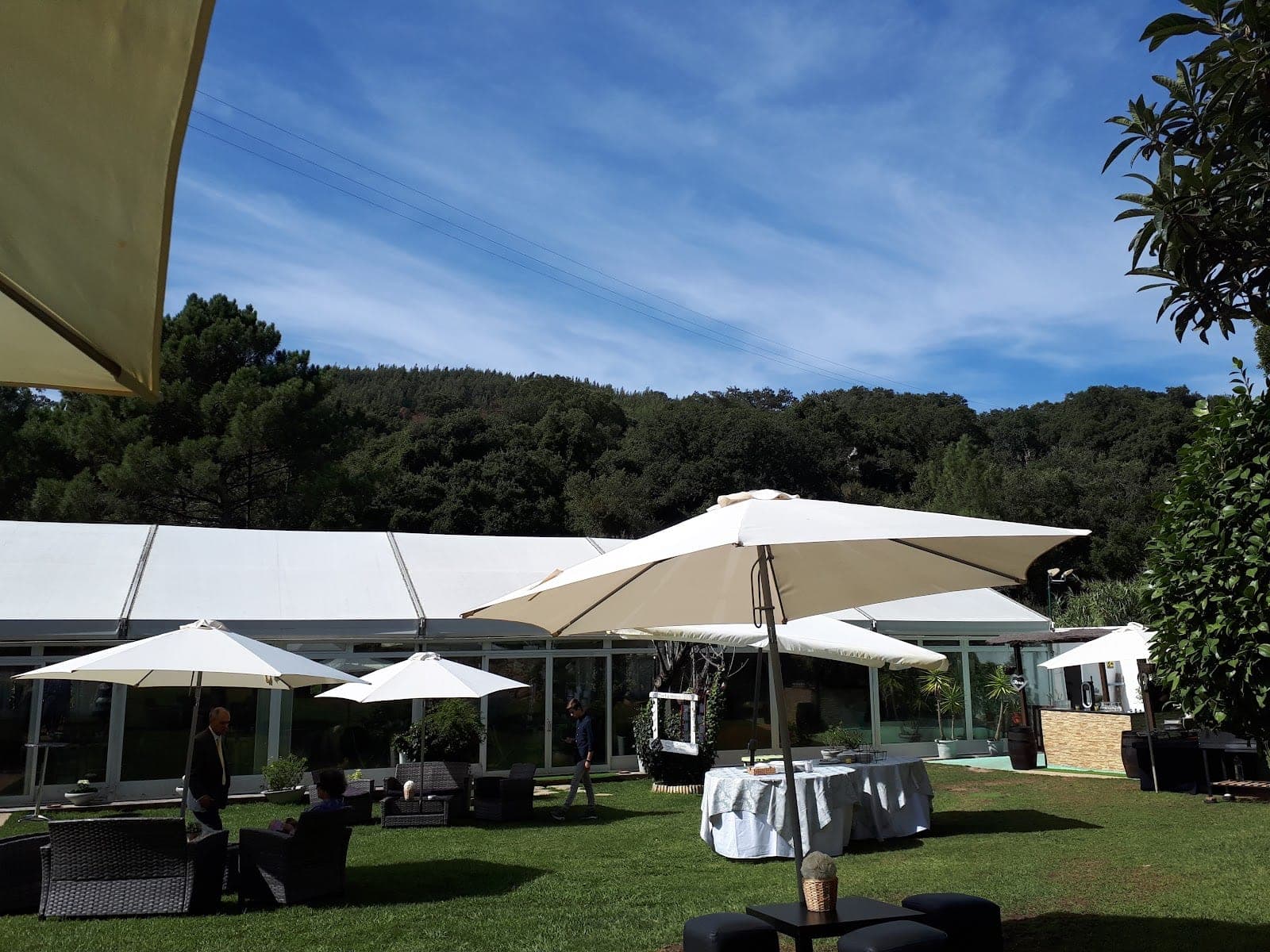 Outdoor event space with tables, umbrellas, and a tent.