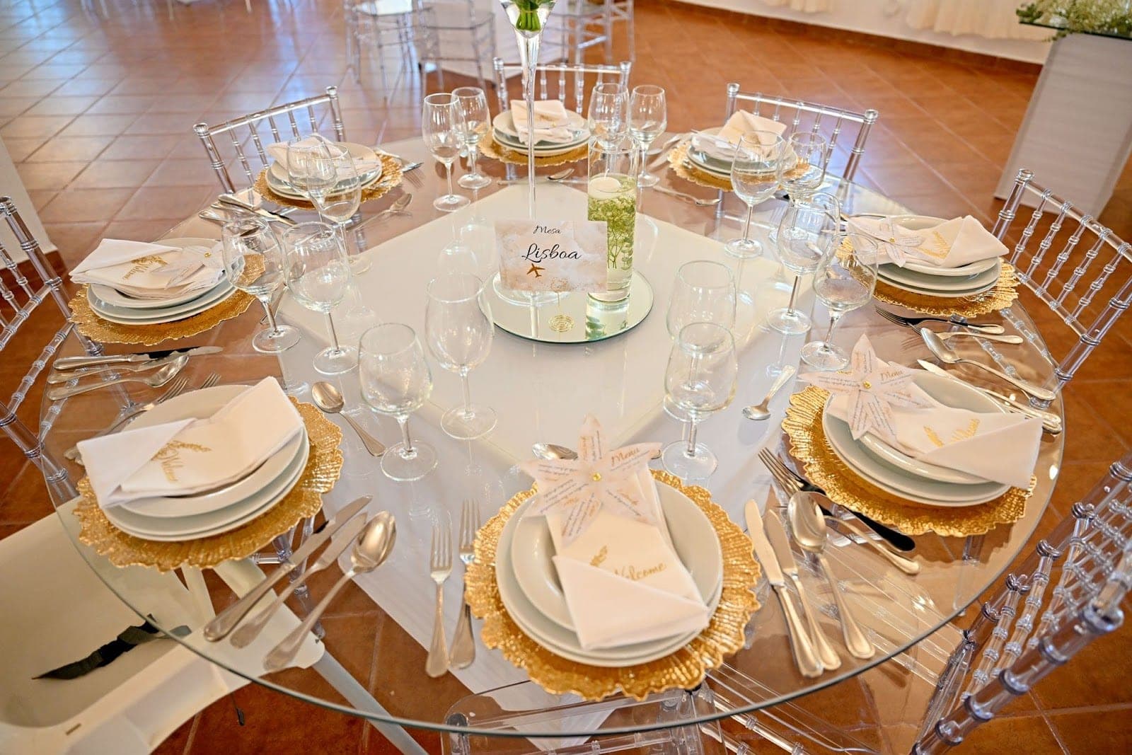 A round table set for a wedding reception with gold chargers and white linens.