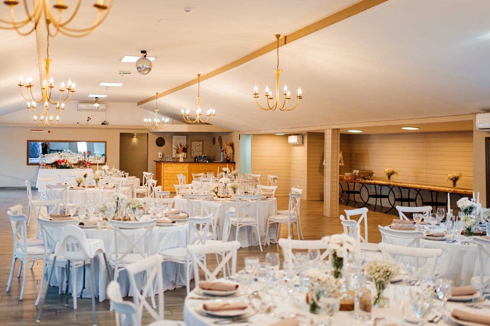 A reception room with round tables set for a wedding.