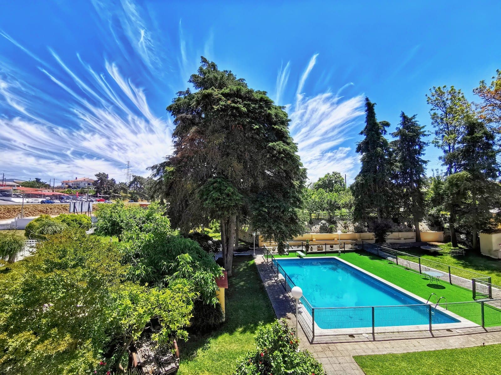 A swimming pool and garden with trees under a dramatic sky.