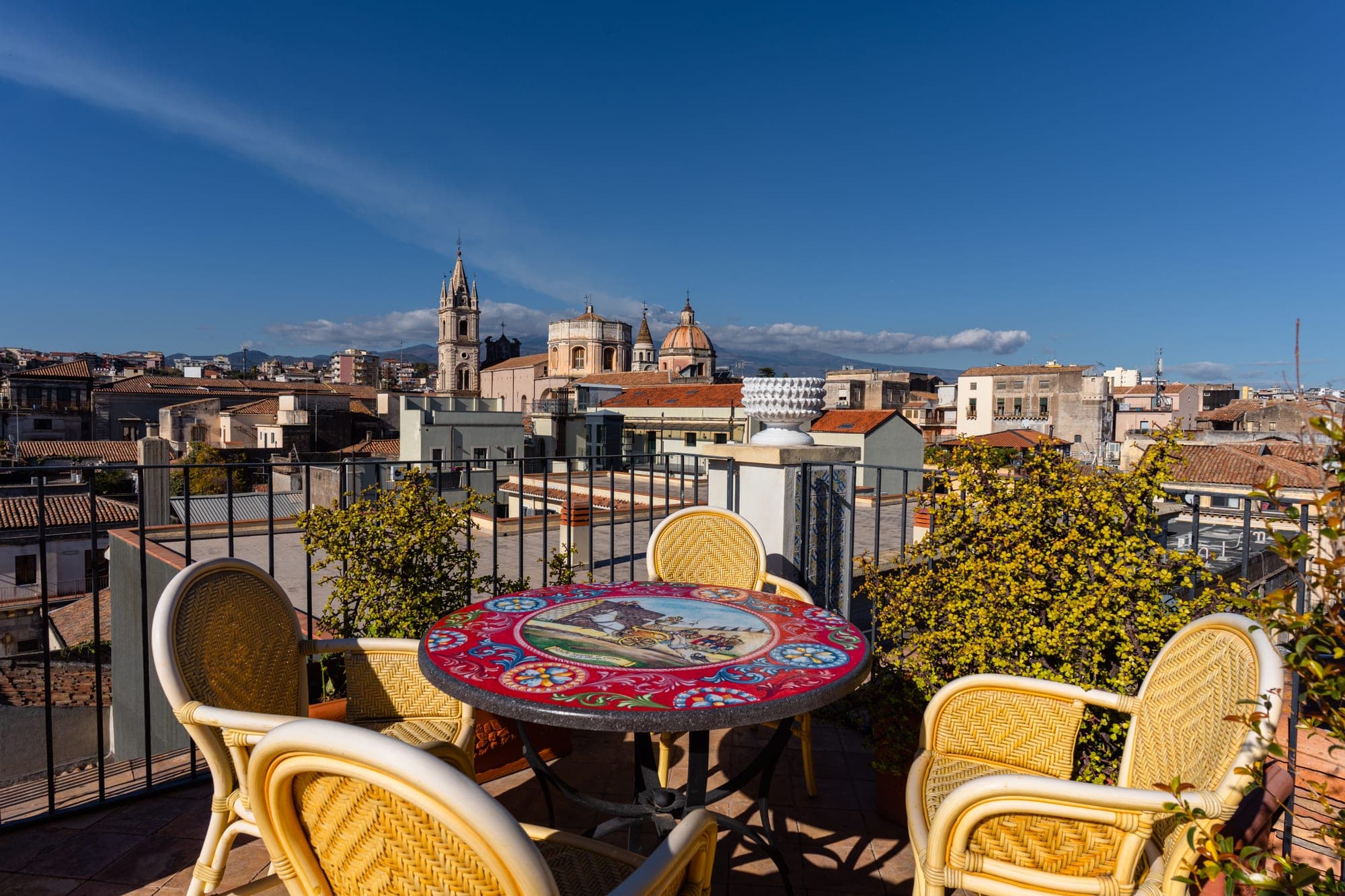 Rooftop terrace with table and chairs overlooking a town with churches.