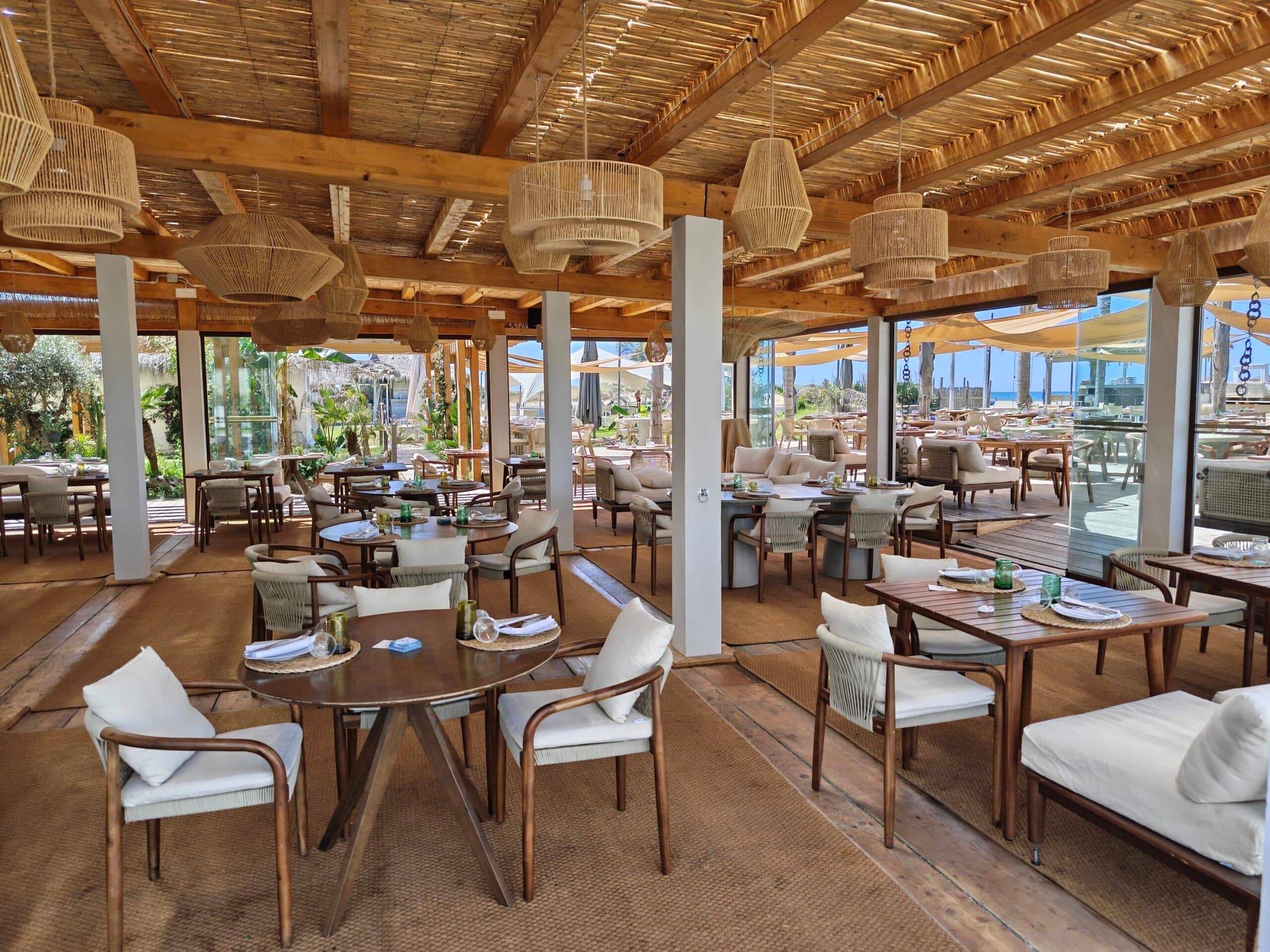 Restaurant interior with tables and chairs, overlooking the sea.
