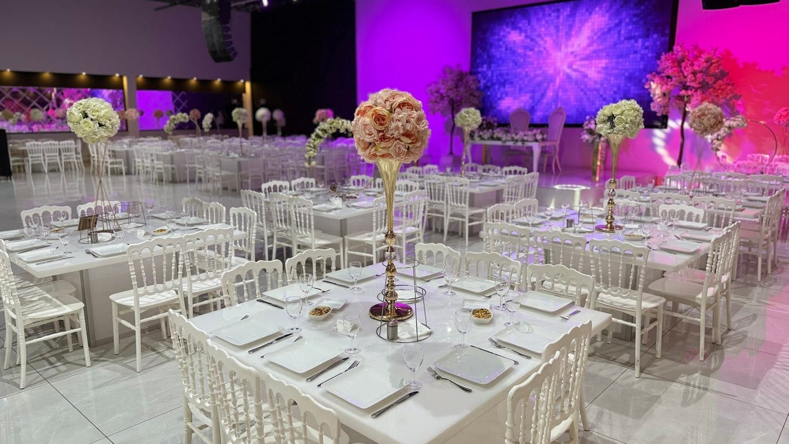 Reception room set for a wedding with white tables and chairs.