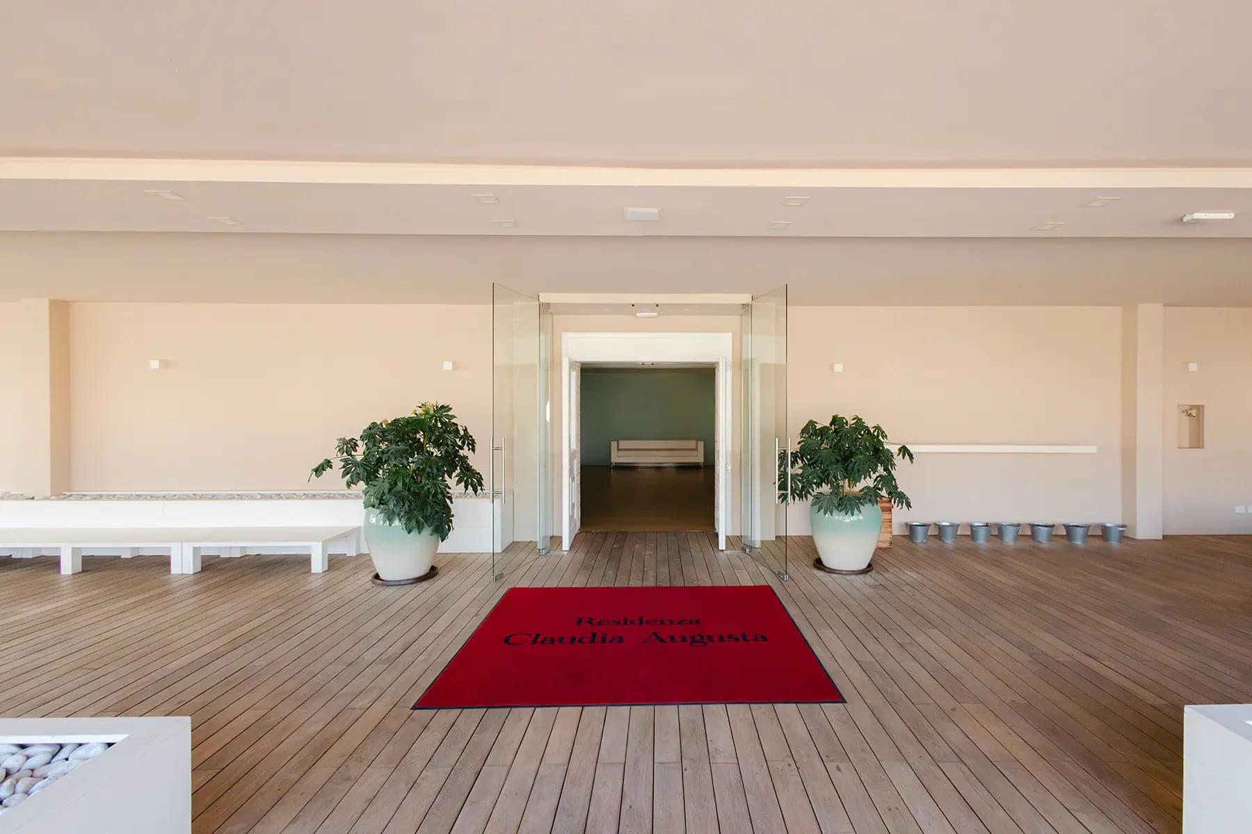Interior of a venue with a red welcome mat and plants.