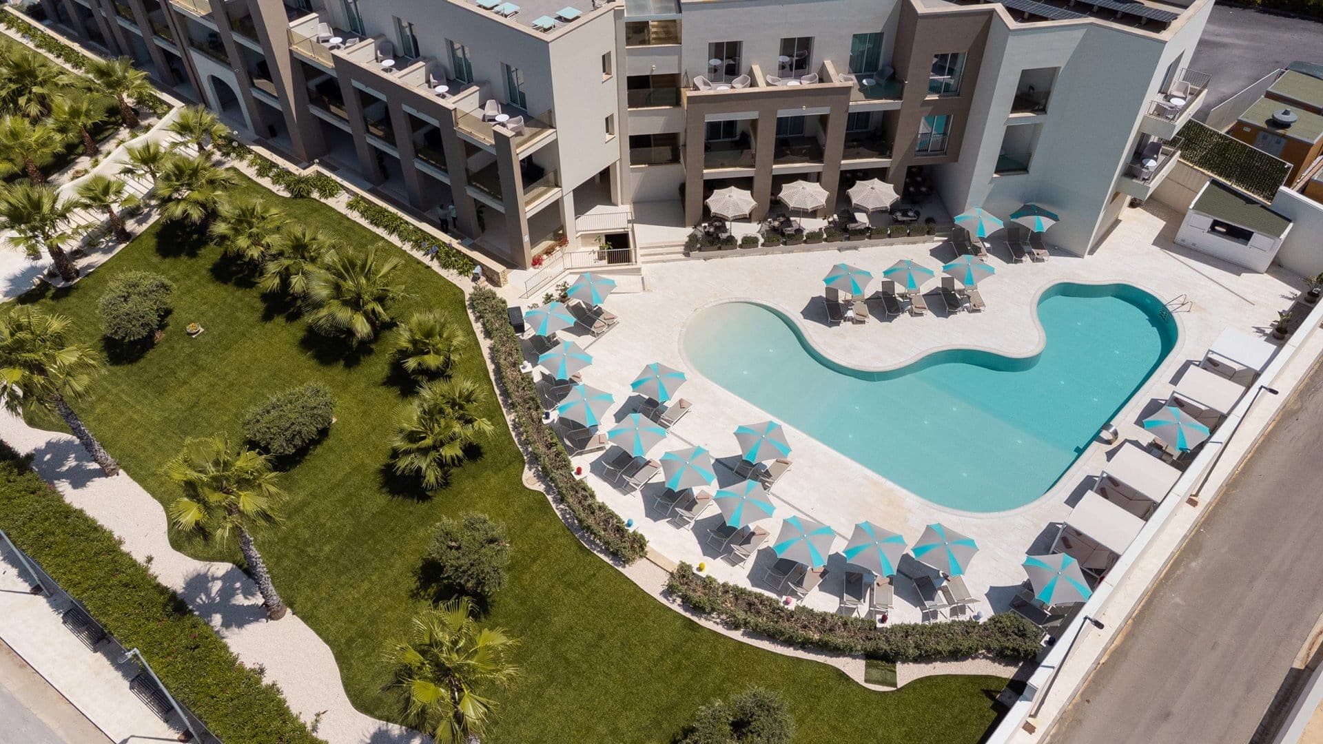 Aerial view of a resort with a swimming pool and palm trees.