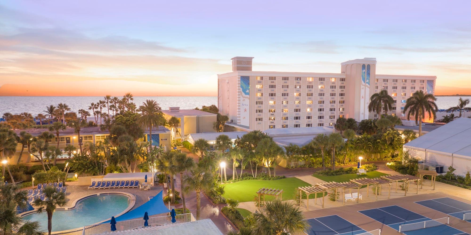 Resort grounds with pool and tennis courts at sunset.