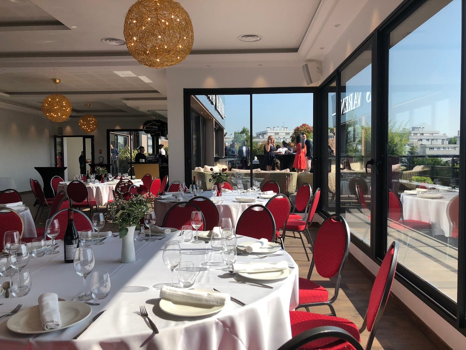 A reception room with tables set for a meal and large windows overlooking a terrace.