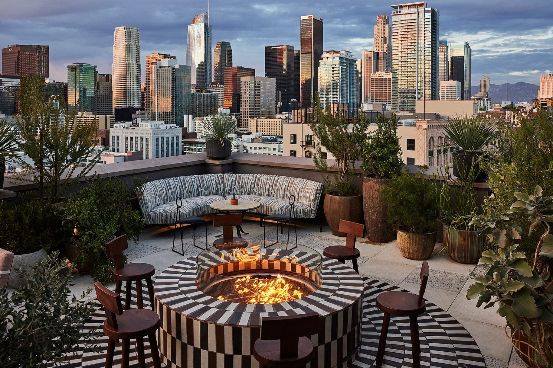 Rooftop terrace with fire pit and city skyline view.