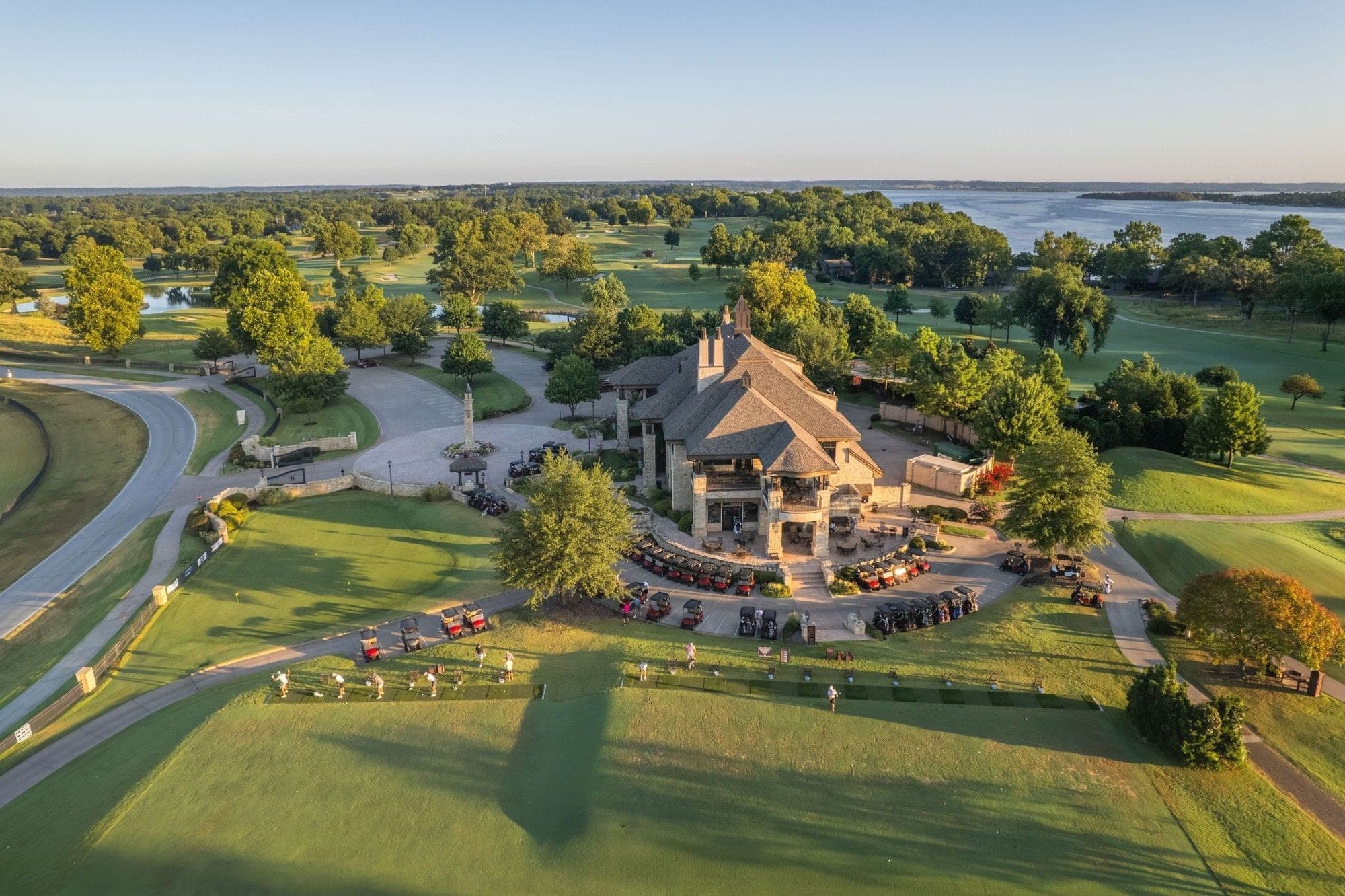 Aerial view of a resort building and golf course with a lake in the background.