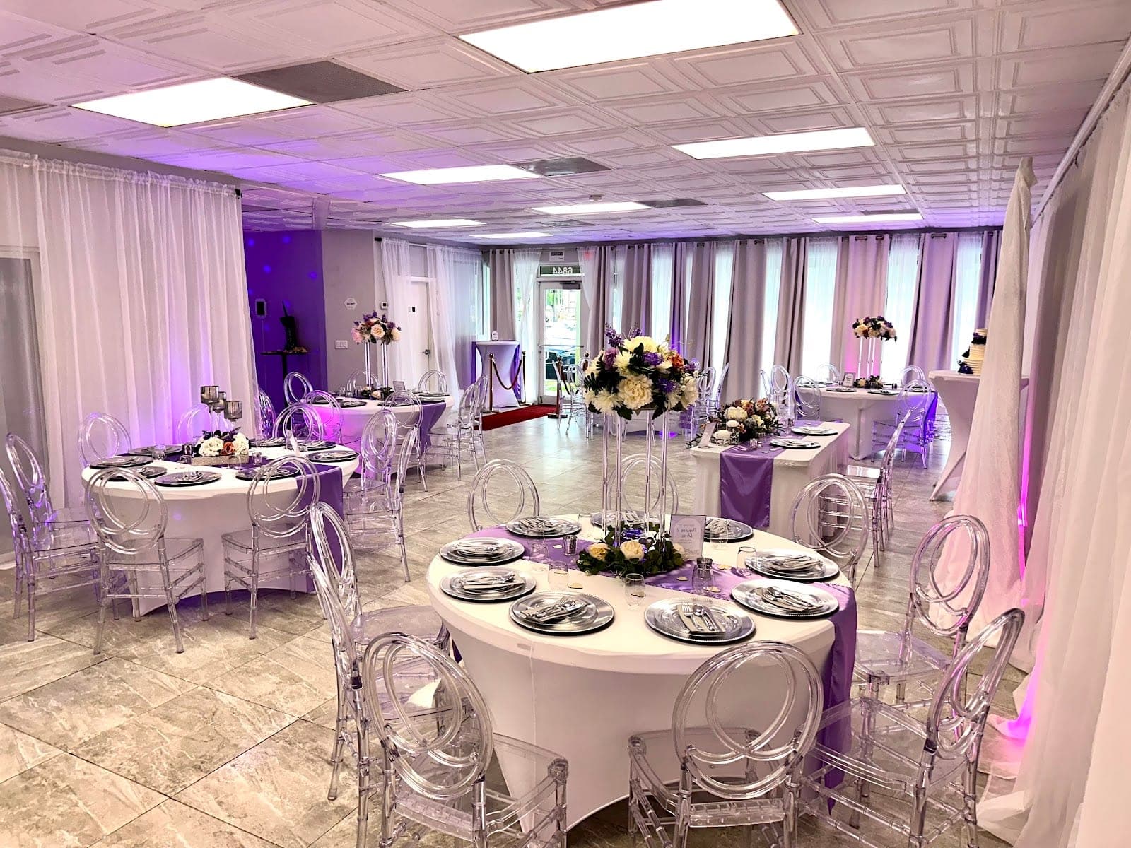 Reception hall with round tables set for a wedding with purple accents.